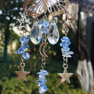 Detail of silver butterfly suncatcher with crystal pendants and blue stones in nature