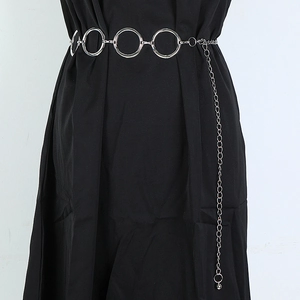 Silver metal waist chain with large rings and dangling tassel on a black dress