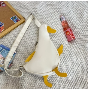 Detail view of cute duck crossbody bag with adjustable strap on a soft textured background