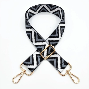 Detail of wide geometric wave pattern bag strap with adjustable gold metal buckle