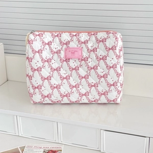 Quilted cotton cosmetic bag with pink bow patterns and a secure top zipper closure
