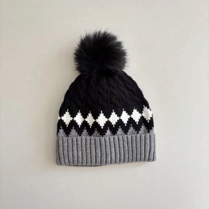 Detailed view of winter knit beanie with black pom-pom and geometric diamond pattern