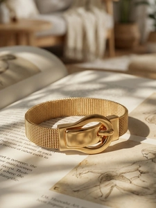 Detail of gold mesh bracelet featuring a vintage buckle closure on a retro book background