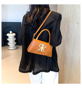 Close-up of a brown leather handbag with a gold R-logo buckle on a shoulder strap