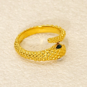 Macro view showing intricate snake scale texture and green gemstone eye on gold ring