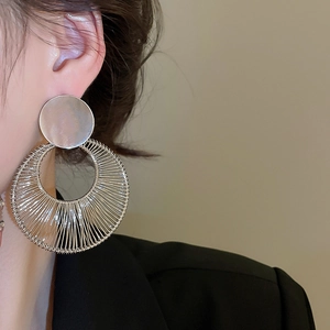 Detailed view of silver geometric round earrings on model for a minimalist fashion look