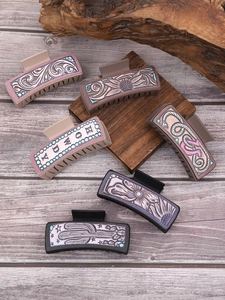 Detailed overhead view of six Western style leather textured square hair claw clips on wood