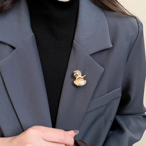 Détail d'une broche cheval à bascule dorée sur le revers d'un costume gris foncé