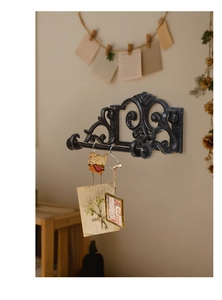 Macro view of vintage cast iron wall rack with scrollwork details and black hooks