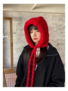 Détail de la cagoule en tricot rouge avec de longues nattes et une maille texturée
