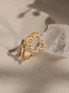 Détail d'une bague trèfle dorée ornée de zircons blancs étincelants et de perles