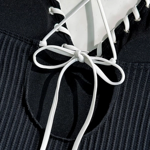 Detail of black ribbed fabric with lace-up eyelets and white elastic cord knot
