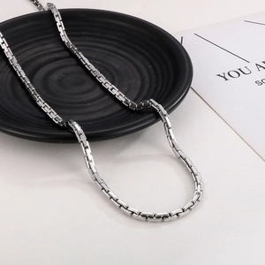 Silver square box chain necklace in minimalist titanium steel on a black ceramic plate