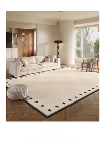 Detail view of cream chenille rug with minimalist black geometric border on wood floor
