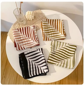 Flat lay of four elegant silk-textured square scarves with geometric patterns in various colors