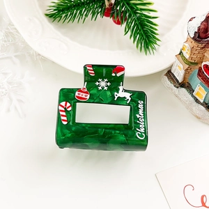 Green Christmas hair claw clip with festive snowflake patterns and white text detail