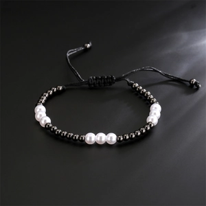 Detailed shot of alternating white pearls and black metallic beads on a woven bracelet