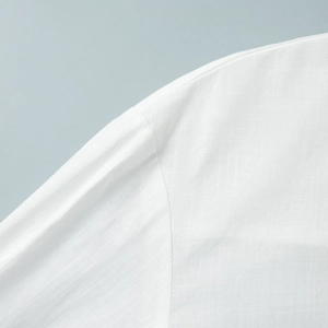 Close-up of white linen shirt dress showing shoulder seam detail and natural fabric texture