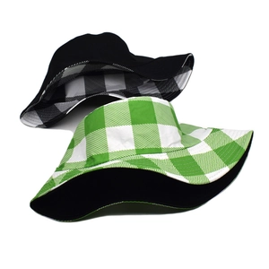 Detail of reversible bucket hat in solid black and green checkered cotton fabric