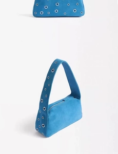 Detail view of bright blue suede bag featuring silver metal eyelets and zipper closure