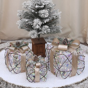 Detail of three brown woven Christmas gift boxes with gold bows and pine cone accents