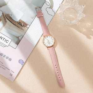 Detail of pink suede strap women watch with rose gold case on aesthetic magazine background