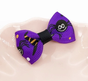 Detail of purple pet bow with black cartoon spider and yellow dots on pink ceramic plate