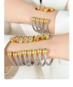 Close-up of stacked cable bracelets with multicolor stones and gold tone accents