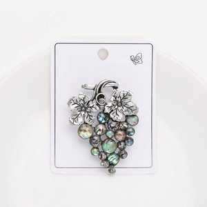 Detail of vintage silver grape brooch with iridescent beads on a white display card
