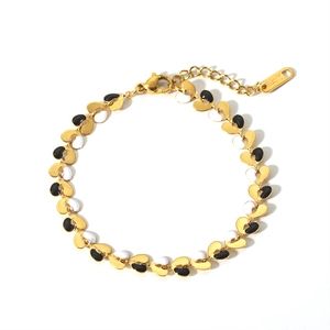 Gold-plated stainless steel bracelet with black and white heart enamel charms on white background