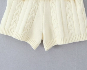 Détail du short en maille blanc cassé avec torsades classiques et finitions en bord-côte