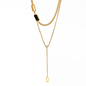 Detail of gold Y-necklace with black enamel squares and sparkling zircon pendant