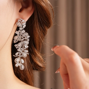 Gros plan de boucles d'oreilles feuilles de luxe avec zircons portées par un mannequin