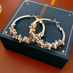 Détail de boucles d'oreilles créoles argentées texturées avec paillettes scintillantes
