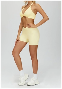 Detail view of light yellow halter yoga bra and high-waist shorts set on a model