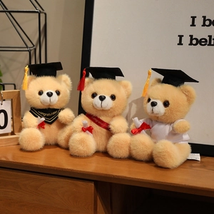 Three plush graduation teddy bears in doctoral caps and gowns on a wooden surface