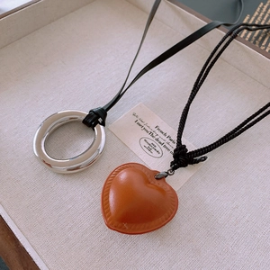 Detail of woven faux leather necklaces with polished silver ring and heart pendants