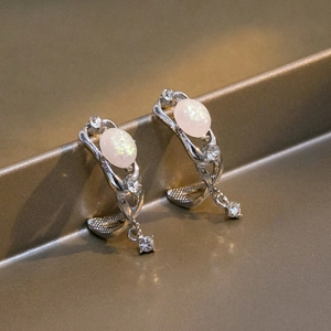 Detailed macro view of silver earrings featuring white opal and sparkling rhinestones
