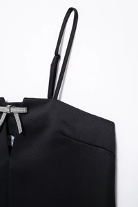 Gros plan détaillé du nœud en strass élégant sur une robe à bretelles en satin noir