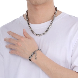 Close-up of 10mm silver pig nose chain necklace and bracelet set worn by male model