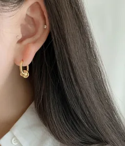 Close-up of minimalist gold hoop earring with a stylish knot charm worn by a model