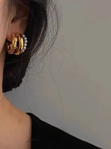 Detail of French vintage layered gold hoop earrings with pearls on female model ear