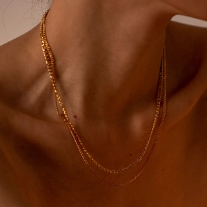 Close-up of a double-layered gold stainless steel necklace on a female collarbone