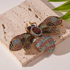 Detailed close-up of a vintage gold bee brooch with multicolored rhinestones on a stone slab