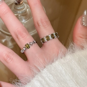 Detailed view of silver oval green gem rings with small white diamonds on finger