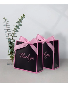 Detail of black gift bags with pink bow decoration and Thank You script font