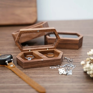 Macro shot of hexagonal walnut wood jewelry box showing fine grain and dual velvet ring slots
