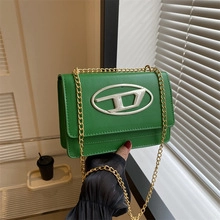 Dettaglio borsa tote in pelle verde con logo D argento e tracolla a catena dorata