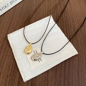 Minimalist wax cord oval pendant necklace in gold and silver finish with shell texture
