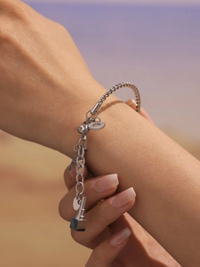 Silbernes Armband mit Stern- und Herzanhängern am Handgelenk mit weichem Hintergrund